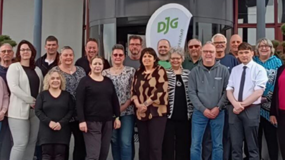 Eine Menschengruppe steht mit Blick zur Kamera vor einem Hoteleingang