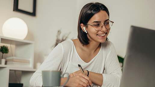 Das Foto zeigt eine Frau, die im Homeoffice ist und gerade an einer Videokonferenz teilnimmt.