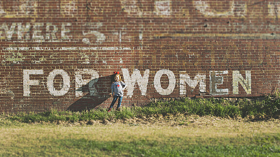 Ehrgeizige EU-Roadmap für Frauenrechte gefordert Ein Mädchen steht vor einer Wand auf der For Women steht