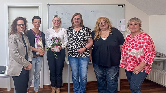 Eine Gruppe Frauen steht vor einem Whiteboard und blicken in Richtung Kamera
