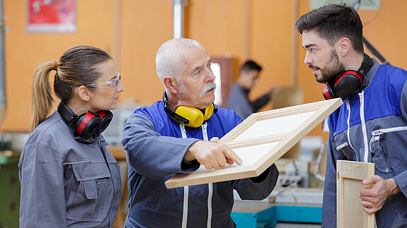 Handwerk Junge Auszubildende im Schreinerhandwerk im Gespräch mit ihrem Ausbilder.