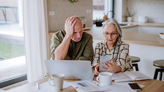 Stressed senior couple calculate expenses or planning budget together at home.