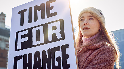 Eine junge Frau hält bei einer Demonstration ein Plakat mit der Aufschrift "Time for Change" hoch.