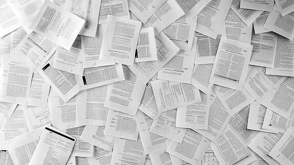 Hunderte einzelne Dokumente und Formulare liegen auf dem Boden neben- und aufeinander. 