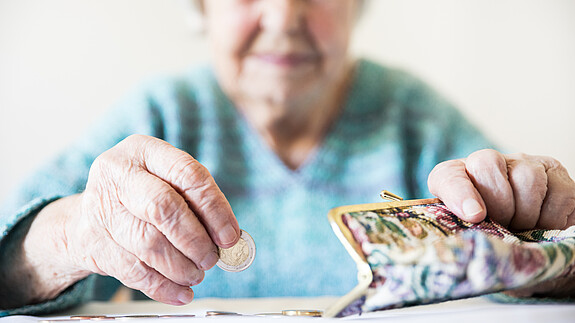 Altersarmut ist weiblich Eine unglücklich wirkende Seniorin zählt am Tisch die wenigen Münzen ihre Pension.