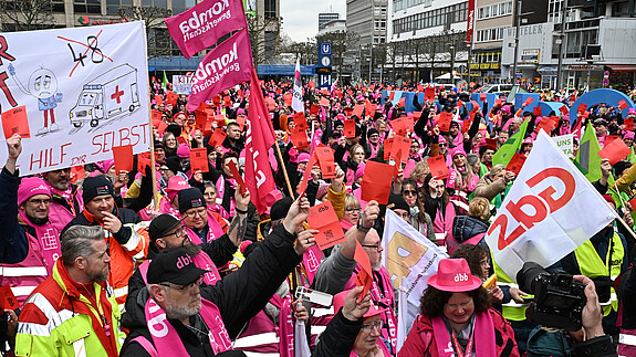 Eine Menschenmenge in bunten Warnwesten und Fahnen