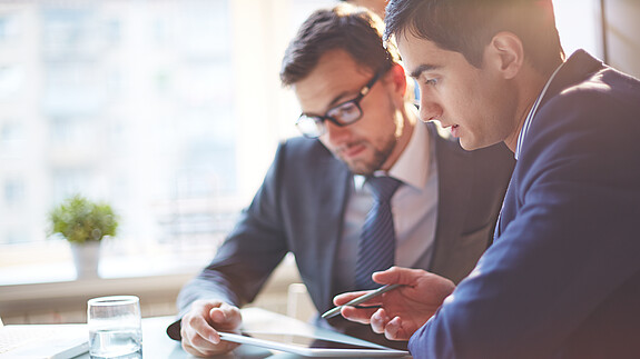 Digitalisierung Zwei Männer im Büro sehen gemeinsam auf Tablet und besprechen sich