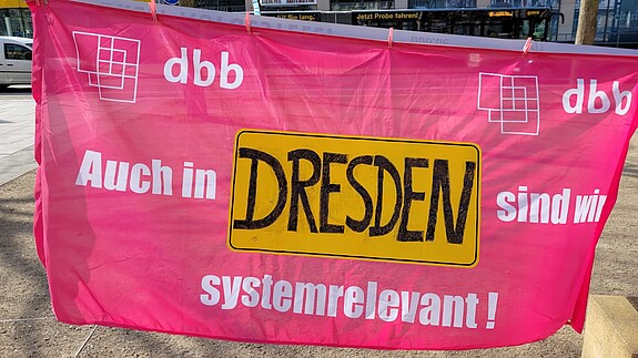 Kundgebung in Dresden Ein Banner wird in die Kamera gehalten, auf dem steht "Auch in Dresden sind wir systemrelevant.""